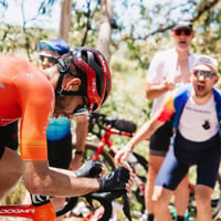 Close up of bike rider racing to the finish line as spectators scream with encouragement from the side lines 